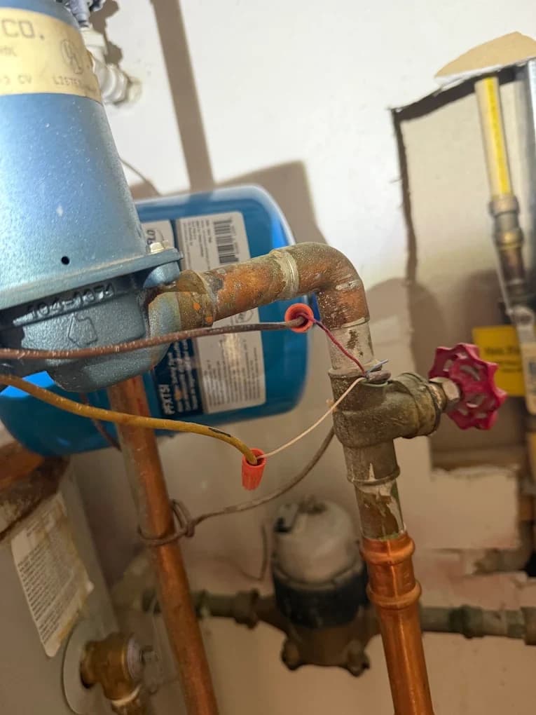 An expansion tank, gas valve and copper piping on a residential heating system, photographed close up